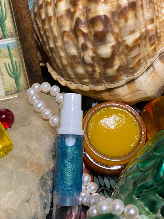 Blue Galactic Sea Flower serum and Cosmic Silk Sealing Balm styled with pearls, crystals, and a large seashell