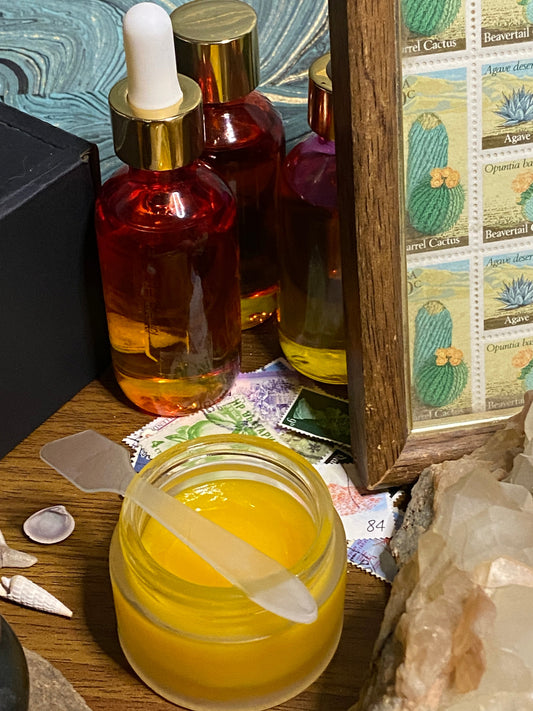 Cosmic Silk Sealing Balm in an apothecary jar surrounded by vintage stamps, amber serum bottles, seashells and crystals